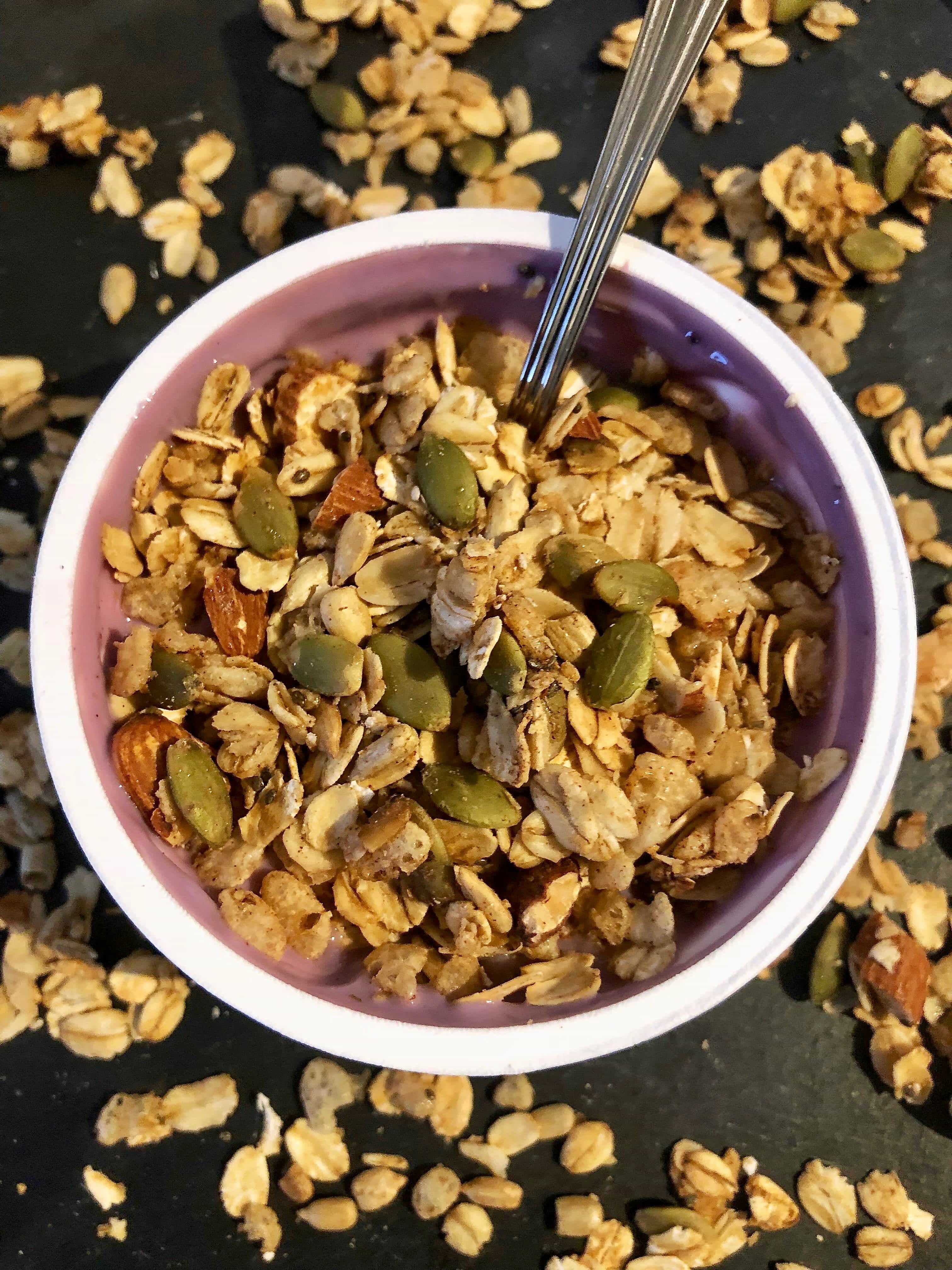 Overhead photo of homemade granola over a cup of blueberry yogurt