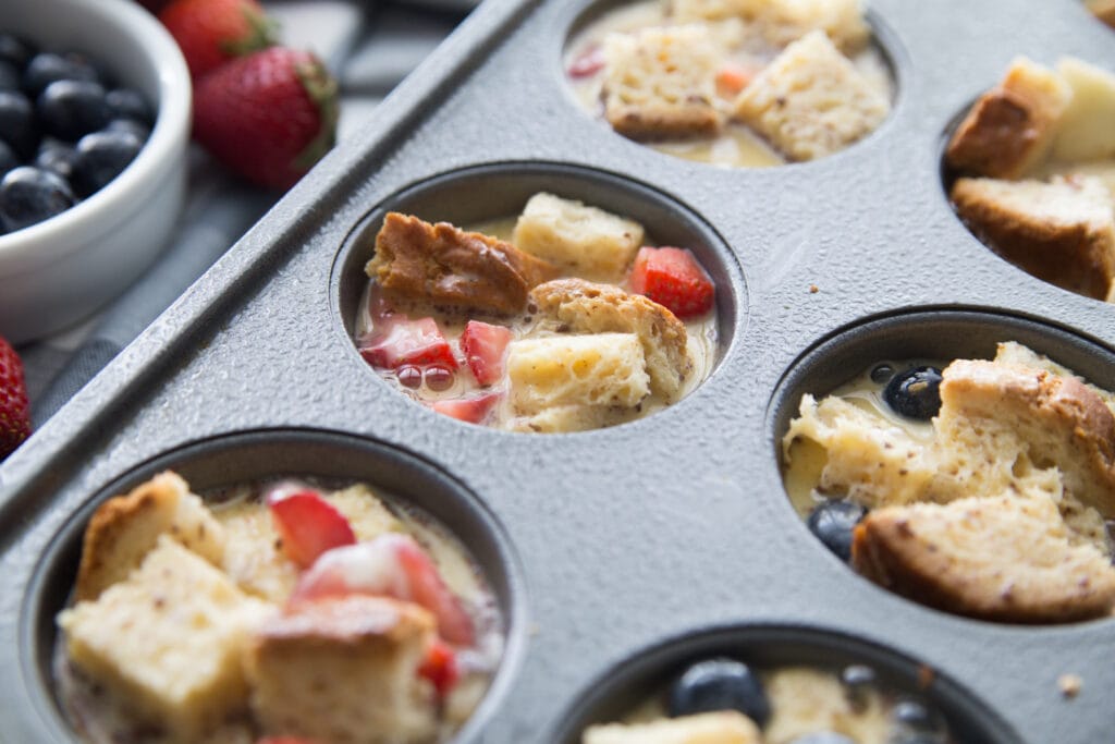 A close up shot of mini french toast casserole cups in a muffin tin before going into the oven 