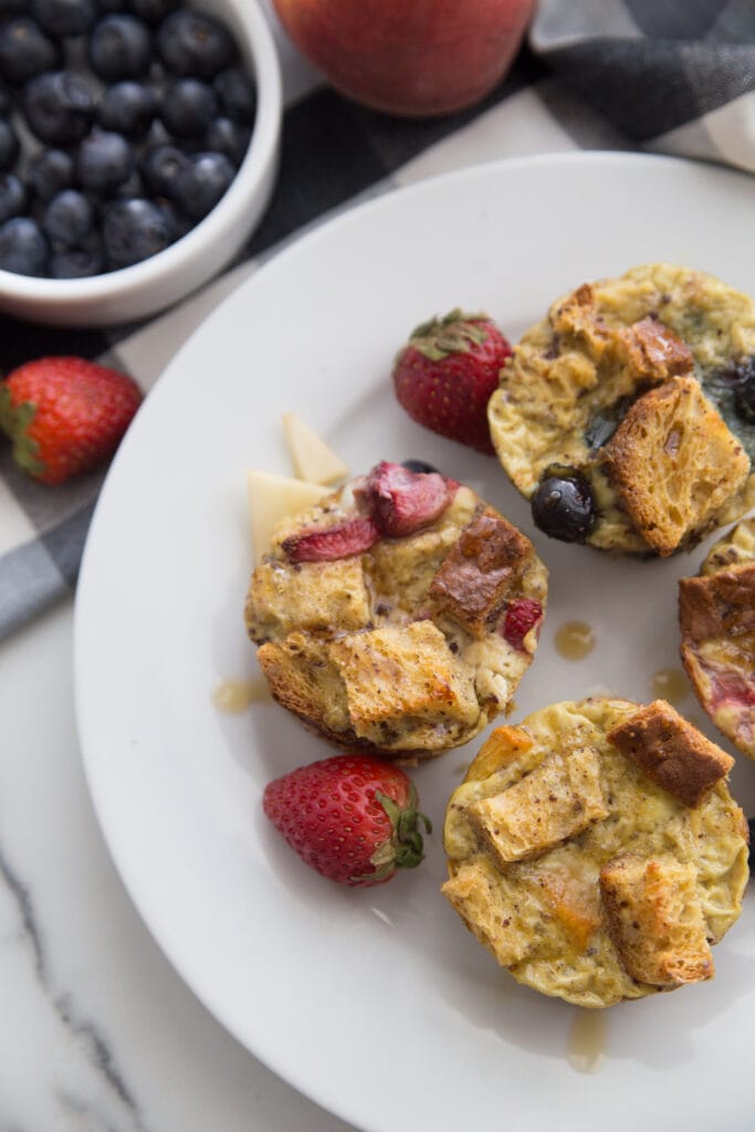 Healthy French Toast Casserole Cups on a white plate topped with different fresh fruit 