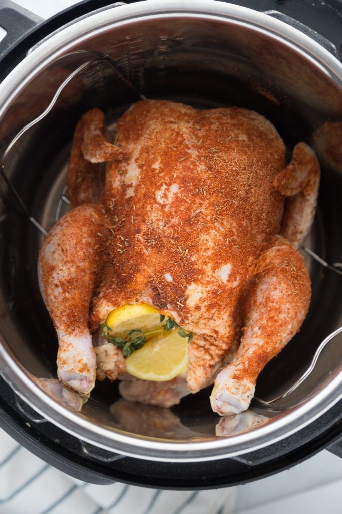A whole chicken covered in spices sitting on a trivet in an Instant Pot