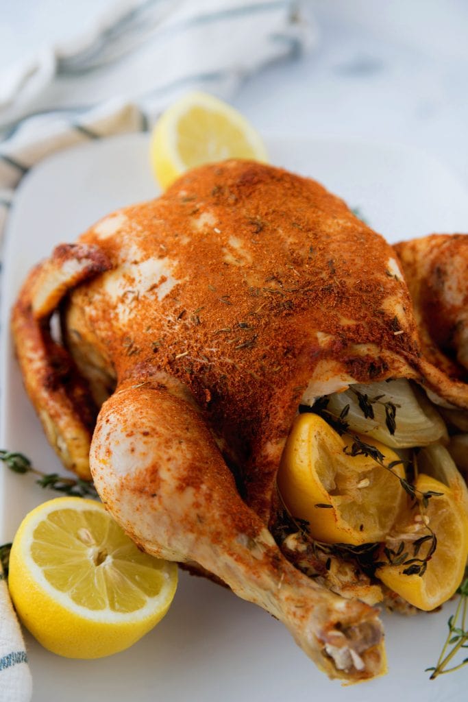 Whole spice rubbed chicken made in the Instant Pot, stuffed with lemons and onion with a white background