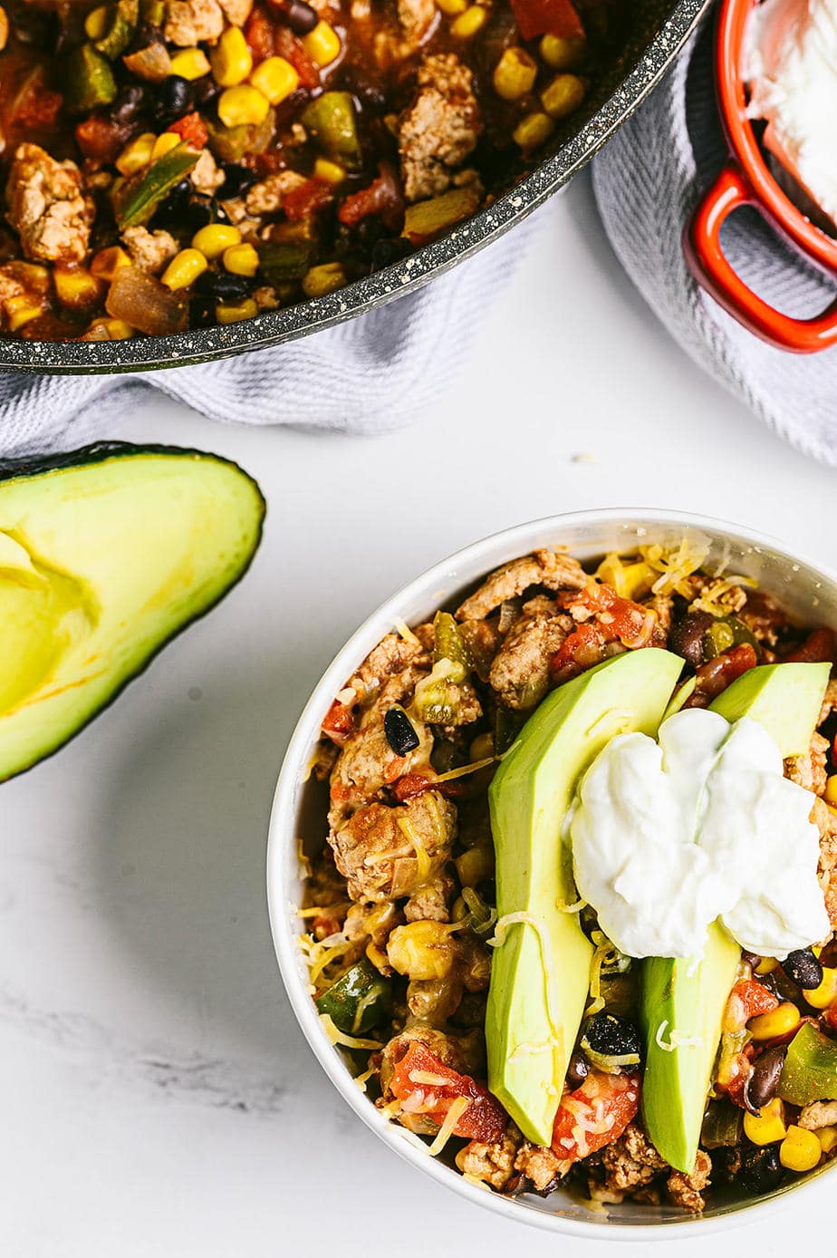 overhead image: a bowl of taco skillet topped with two slices of avocado, some shredded cheddar cheese and a dollop of greeyk yogurt