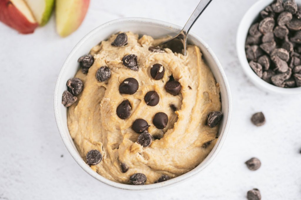 A small bowl cookie dough dip with chocolate chips and apples