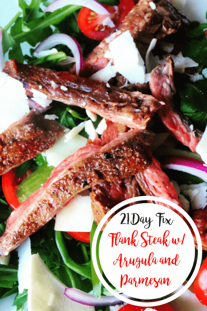 Fresh arugula topped with halved grape tomatoes, sliced red onions, shaved Parmesan cheese and Flank Steak cut into strips on a white plate- with the text overlay 21 Day Fix Flank Steak w/ Arugula and Parmesan in a white circle