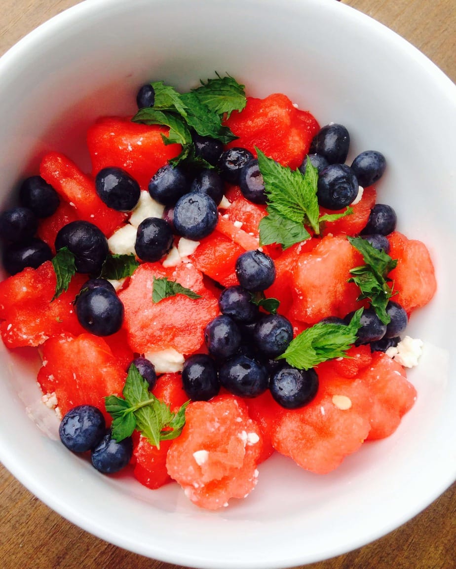 Watermelon, blueberries, feta, and mint mixed up in a white bowl