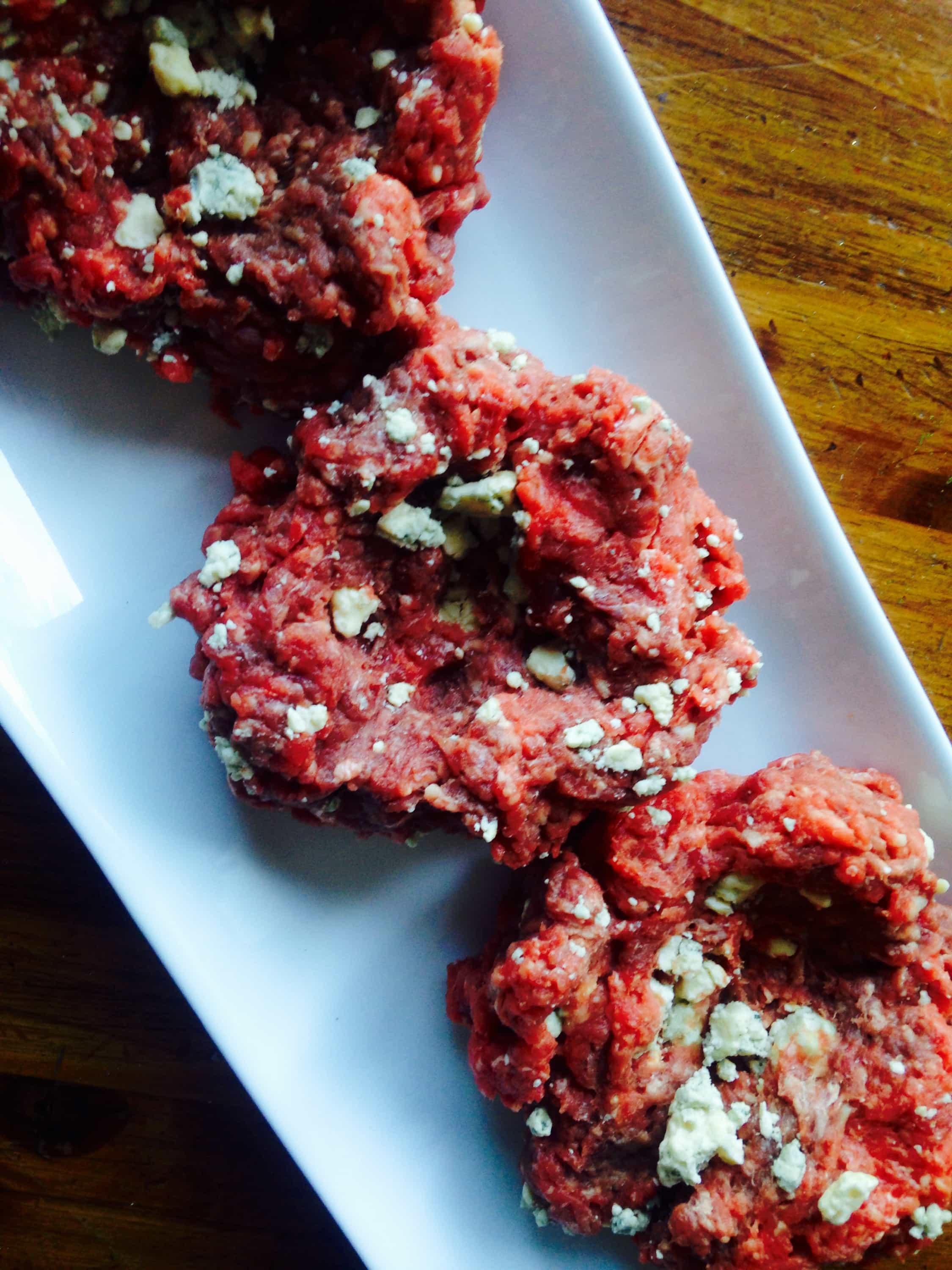 raw sirloin patties with blue cheese crumbles on a long rectangular plate