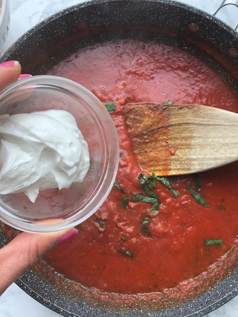 A skillet and a small bowl of plain Greek yogurt for a Healthy Vodka Sauce