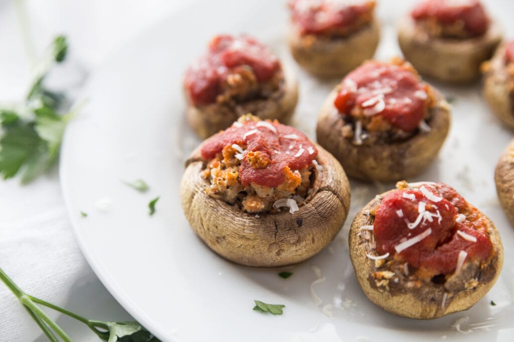 A Plate of Italian Style Stuffed Mushrooms with spicy chicken sausage, parmesan cheese and topped with tomato sauce 