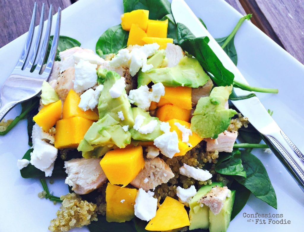 Featured salad photo of avocado mango and quinoa salad on a bed of spinach