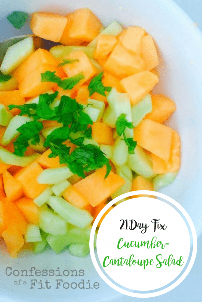 Diced cucumber and cantaloupe in a white bowl topped with fresh mint and a silver spoon resting on the side