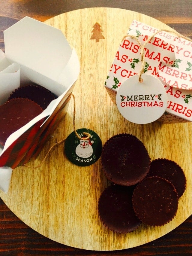Fudge cups on a wooden background with red and green treat boxes decorated with "Merry Christmas".