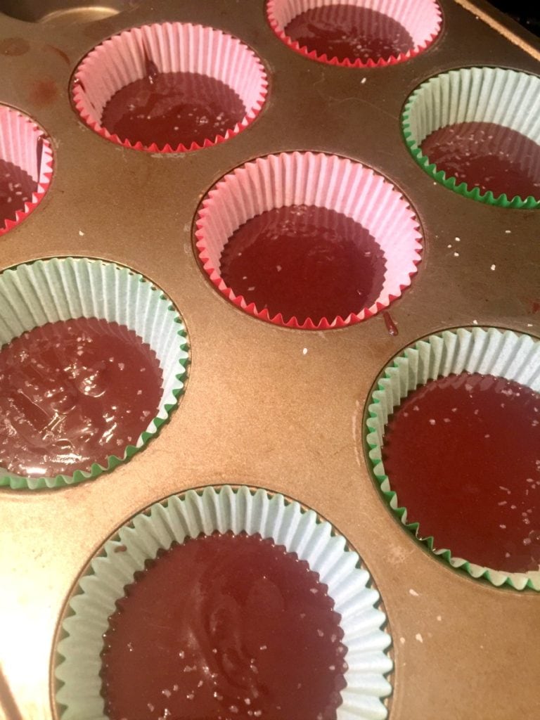 Muffin tin with red and green cupcake liners filled with dairy free fudge, ready for the refrigerator.