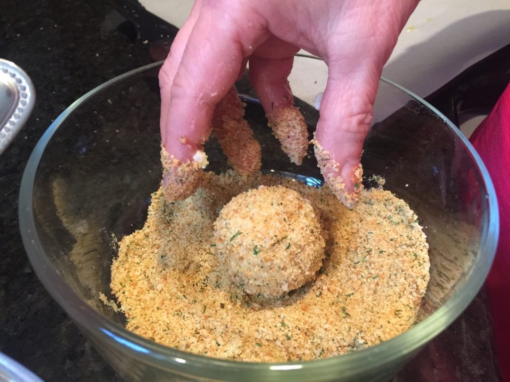 Mini Arancini Rice Ball coated in breadcrumbs in glass bowl full of breadcrumbs
