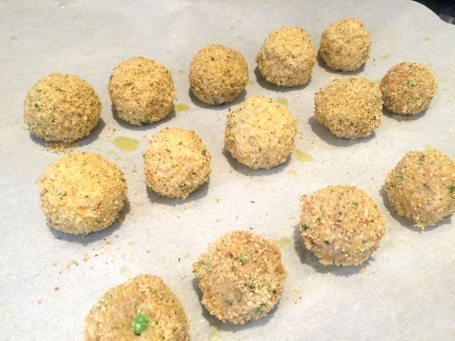 Mini Arancini Rice Balls lined up on a parchment lined baking sheet, ready for the oven