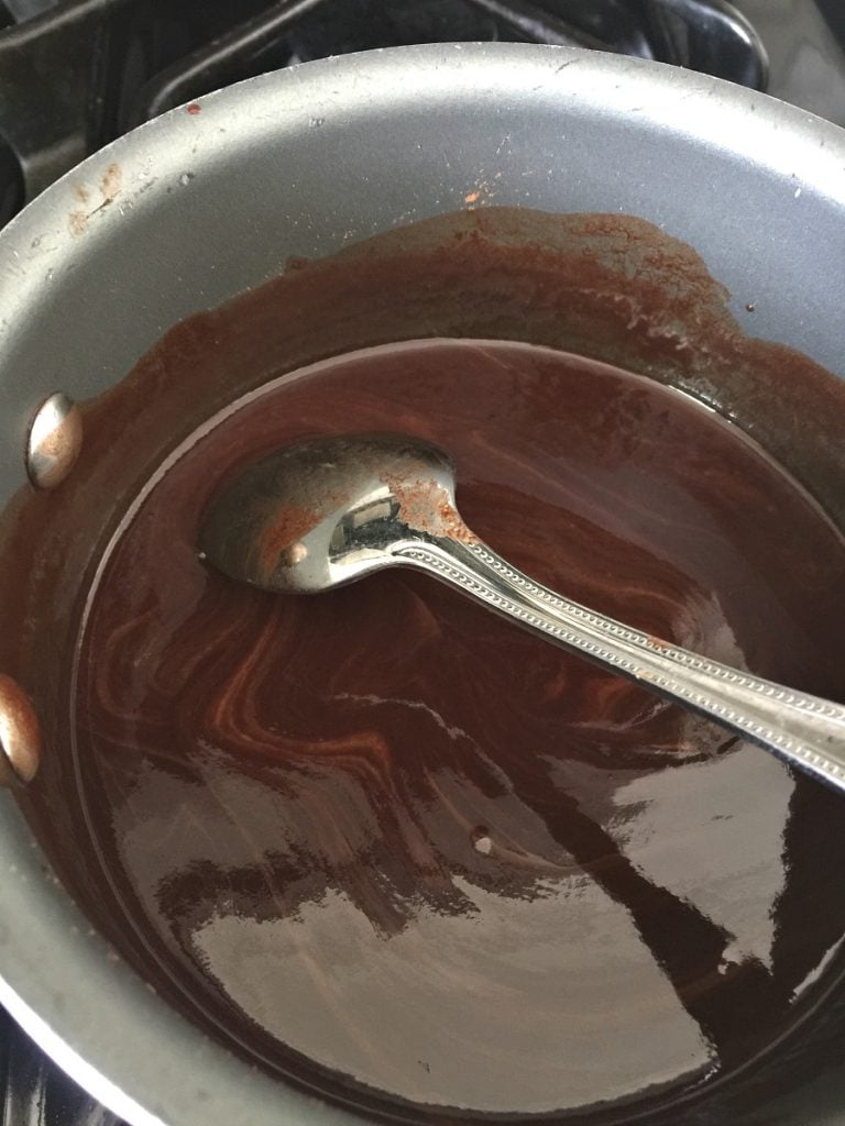 Dairy Free chocolate fondue recipe in a pot on the stove with a spoon turned over in the pot