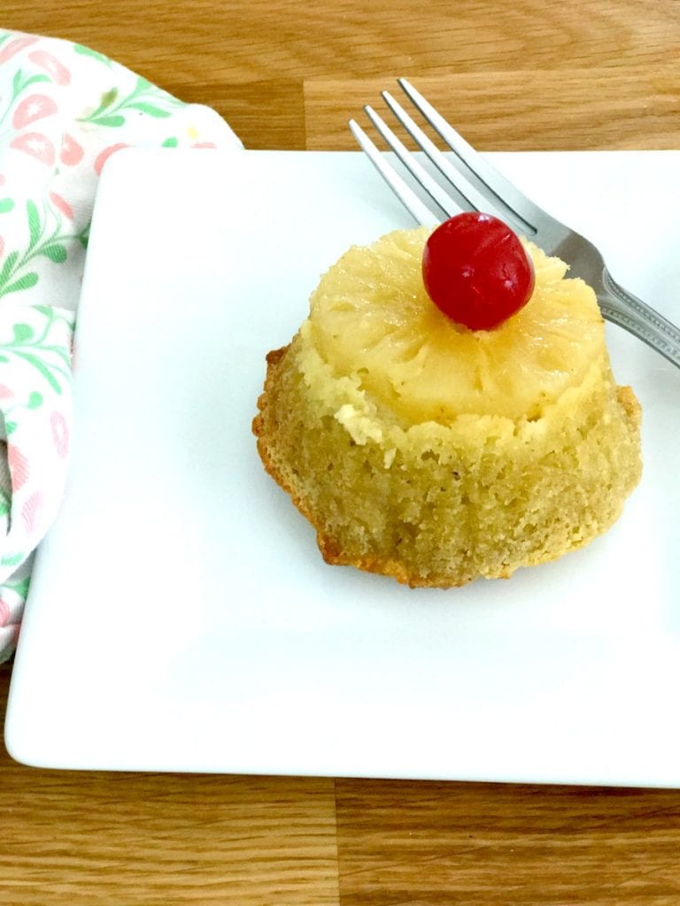 Close up photo of a pineapple upside down cupcake on a white rectangular plate.