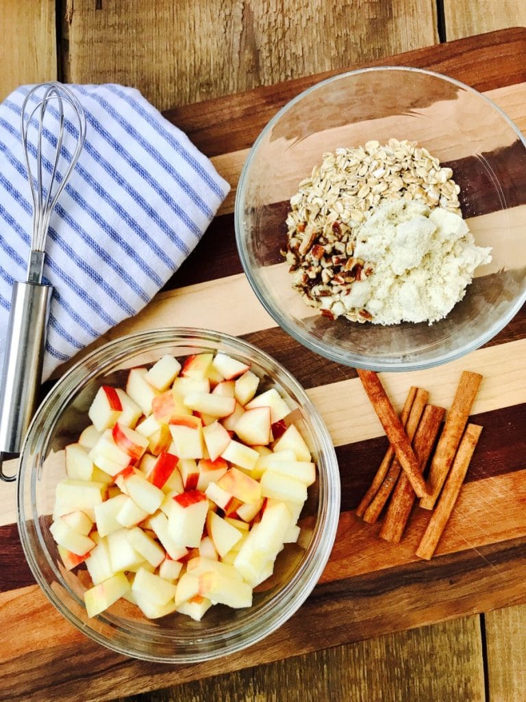 A bowl of apples and oats on a wooded cutting board - ingredients for Instant Pot Apple Crisp