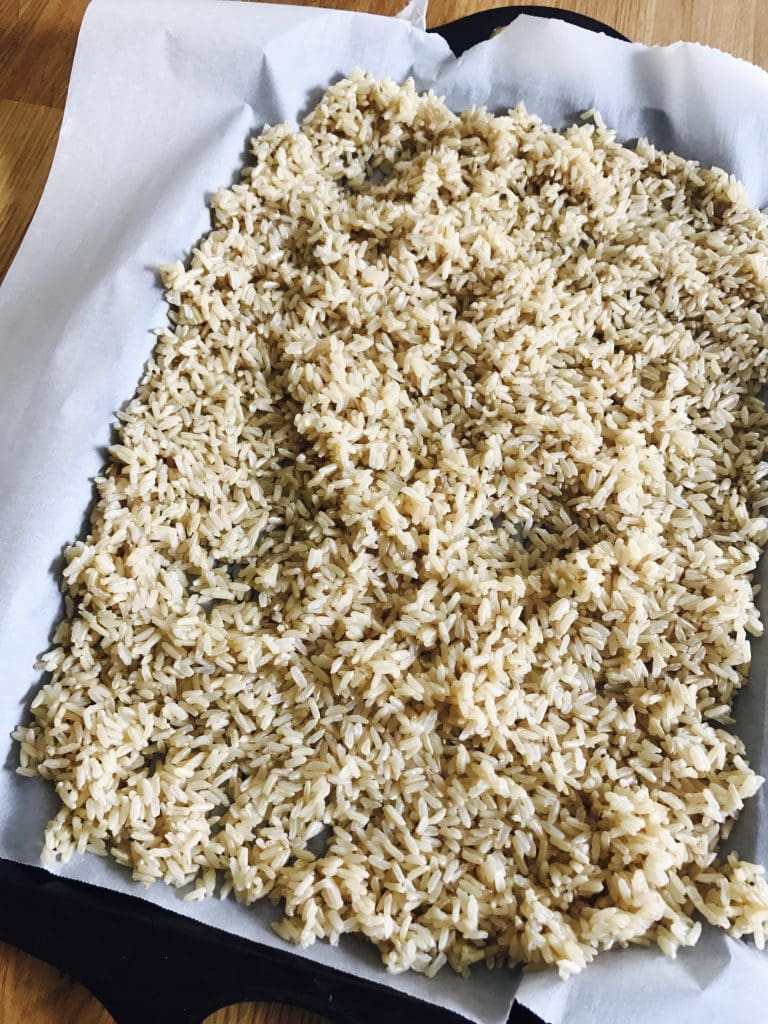 Parchment lined baking sheet filled with cooked brown rice