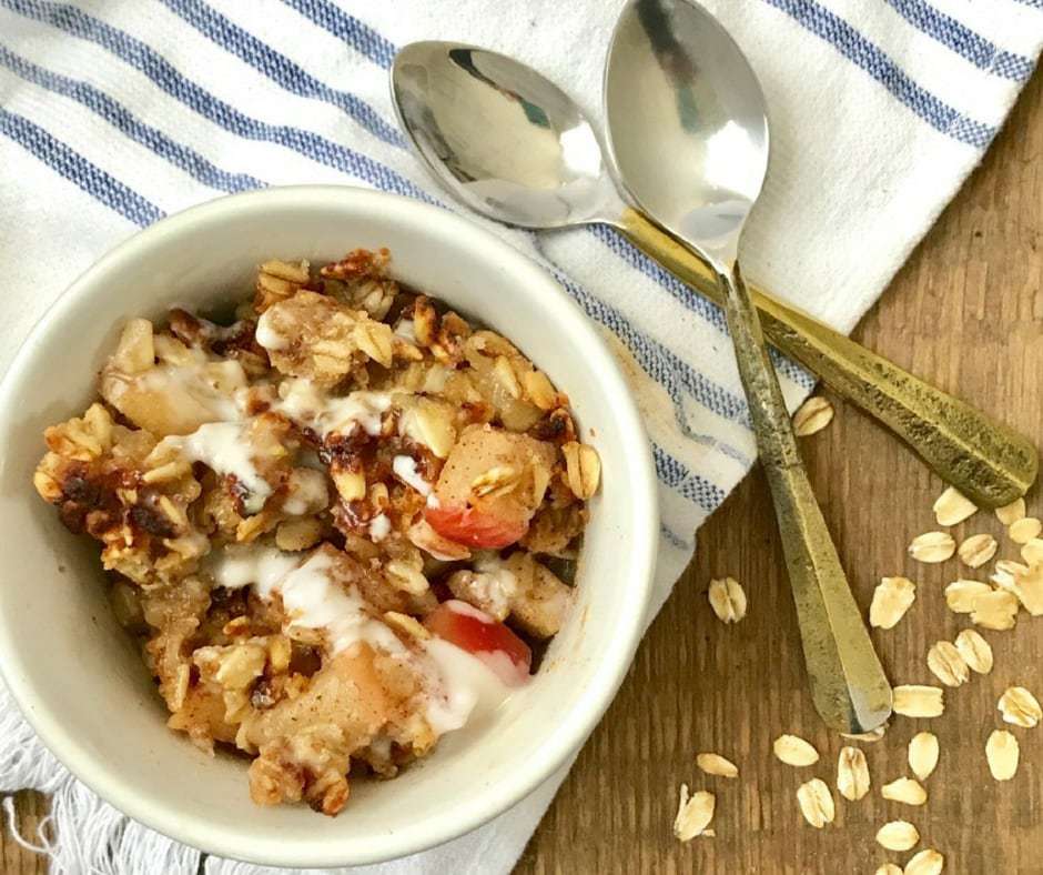 Overhead image: individual bowl of apple crisp with spoons next to the bowl.