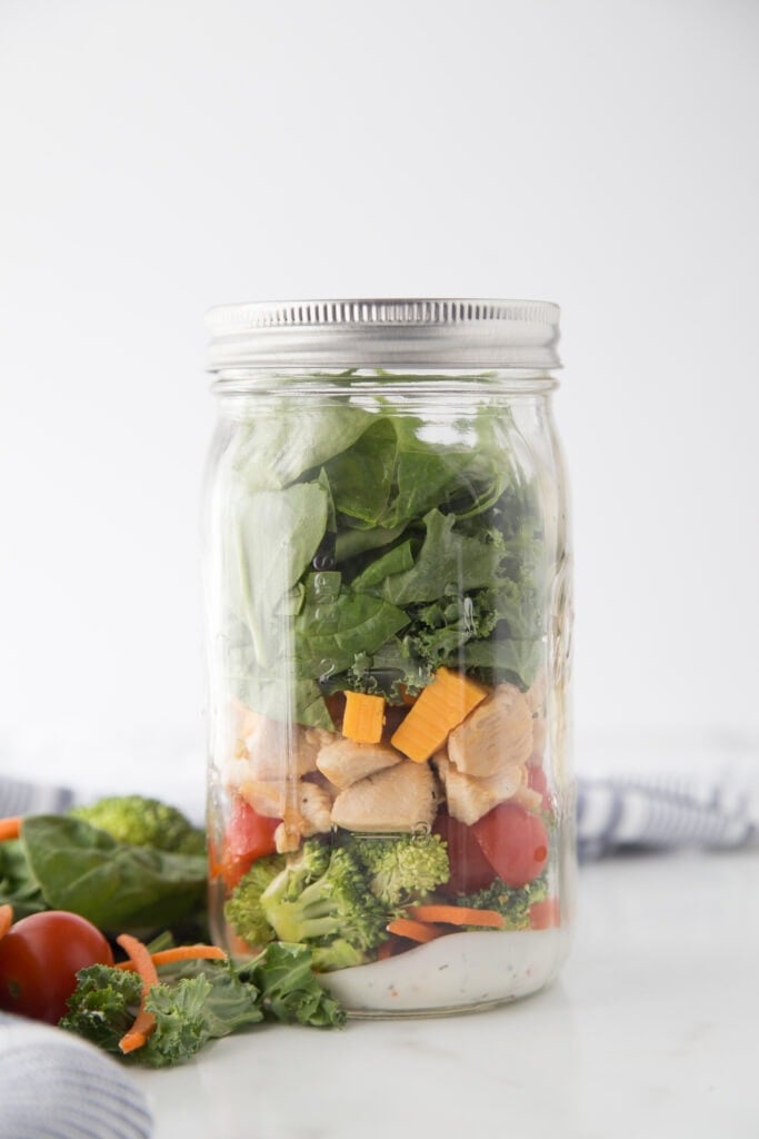 A Jar of BLT Mason Jar Salad with homemade ranch dressing, carrots, broccoli, tomatoes 