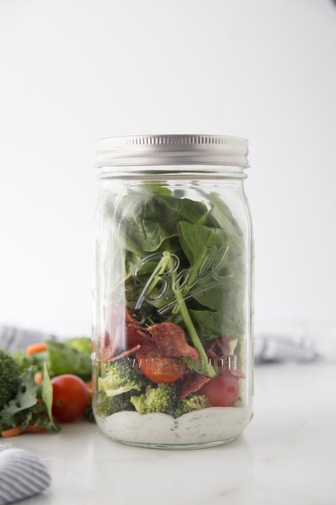 A large 24 oz mason jar meant for mason jar salads filled with ranch dressing and veggies