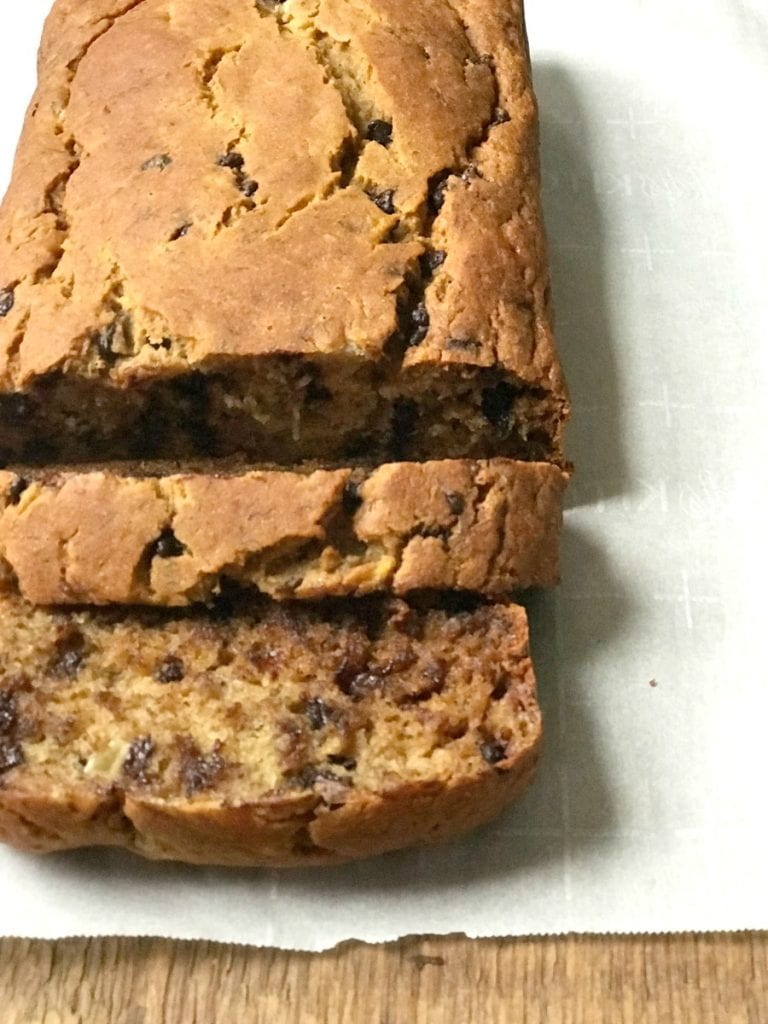 High angle photo of a loaf of healthy banana bread on a parchment lined wooden surface
