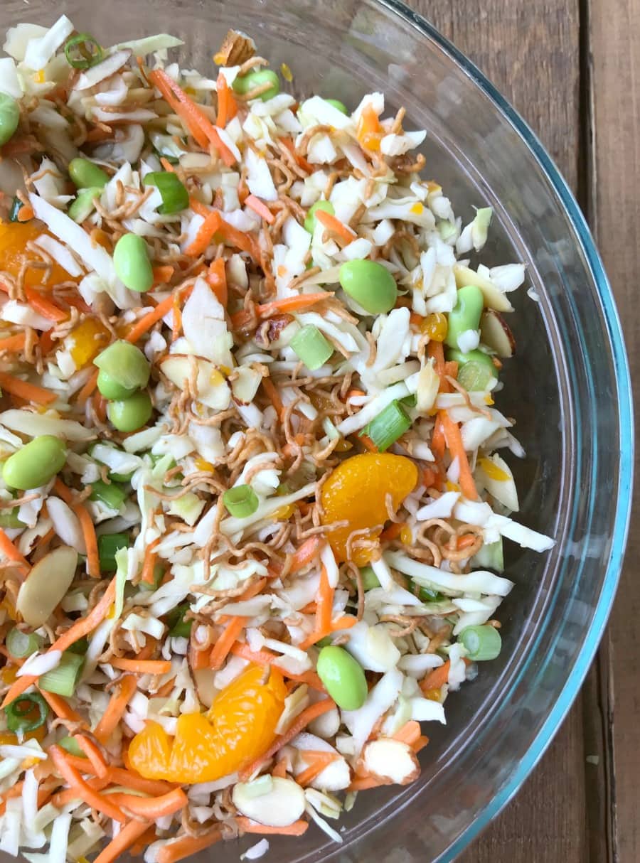 Close up of Ramen Noodle Salad Tossed Together in a glass bowl on a wooden surface