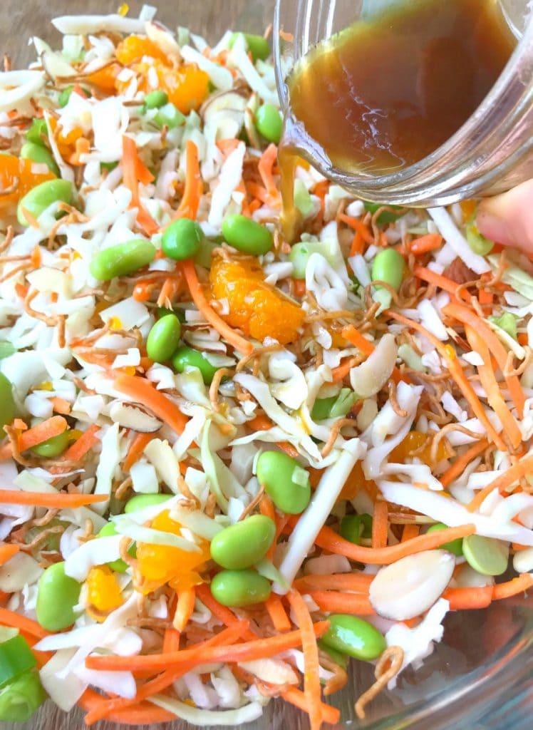 Close up photo of Ramen Noodle Salad with Asian Vinaigrette being poured over top from a glass mason jar