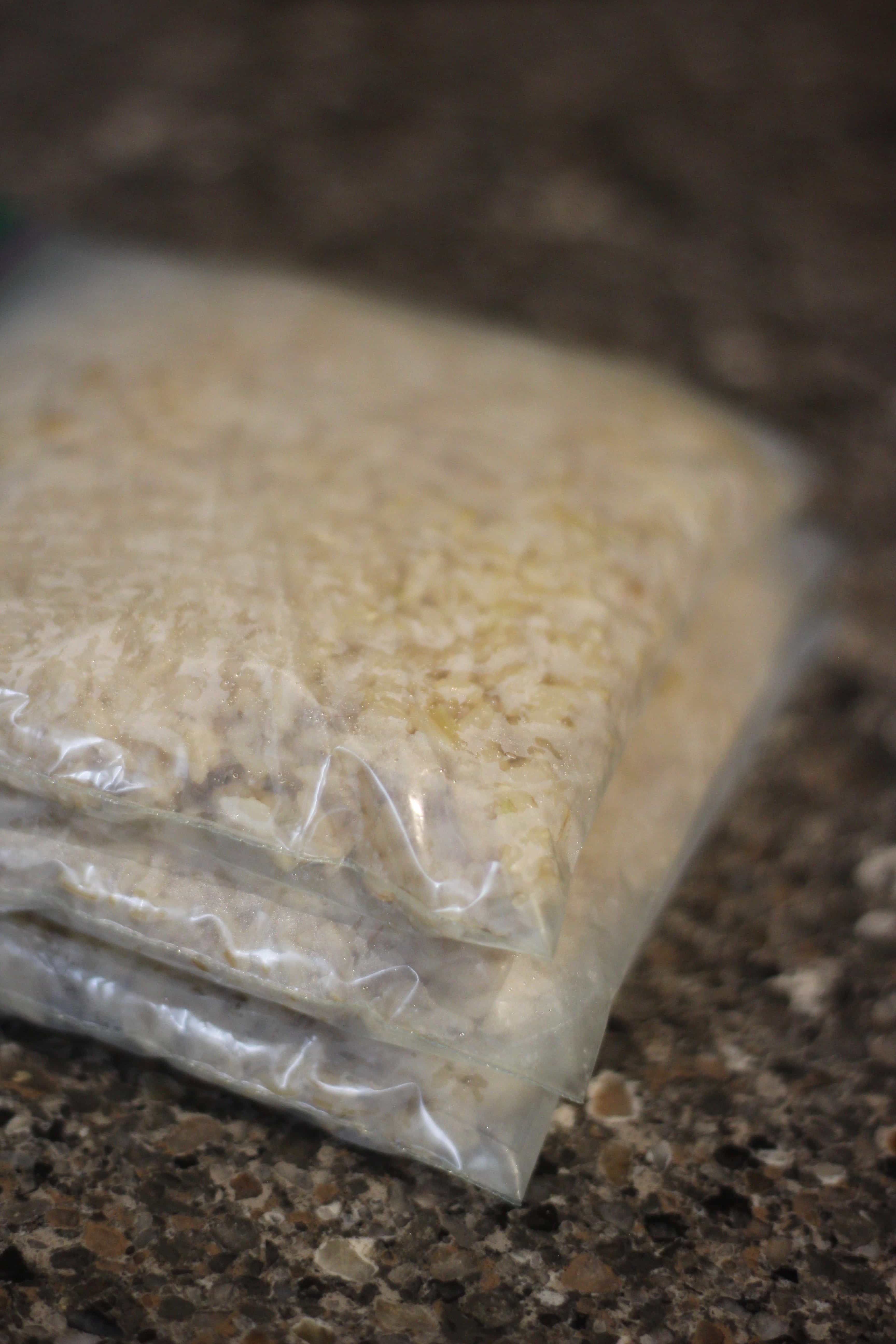 Plastic freezer storage bags filled with brown rice, laying flat on the counter, ready for the freezer