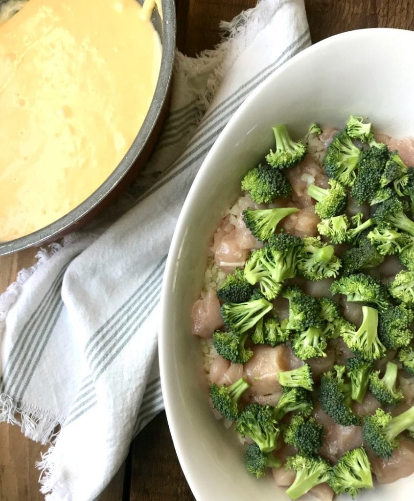 Pan of cheese sauce next to a casserole dish of chicken and broccoli 