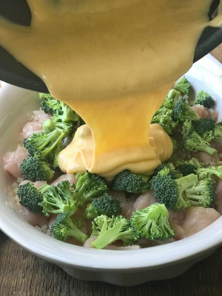 Cheese sauce being drizzled over broccoli and cheddar casserole