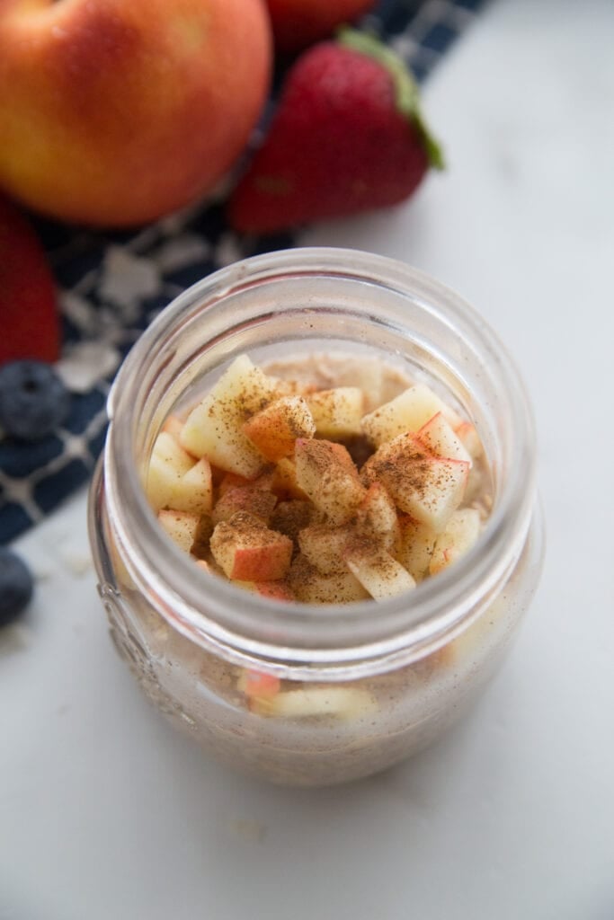 A jar of apple cinnamon overnight oats topped with extra cinnamon 