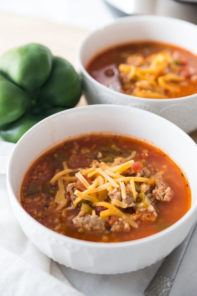 Two bowls of low carb stuffed pepper soup topped with shredded cheddar cheese, made in the Instant Pot and ready for gameday