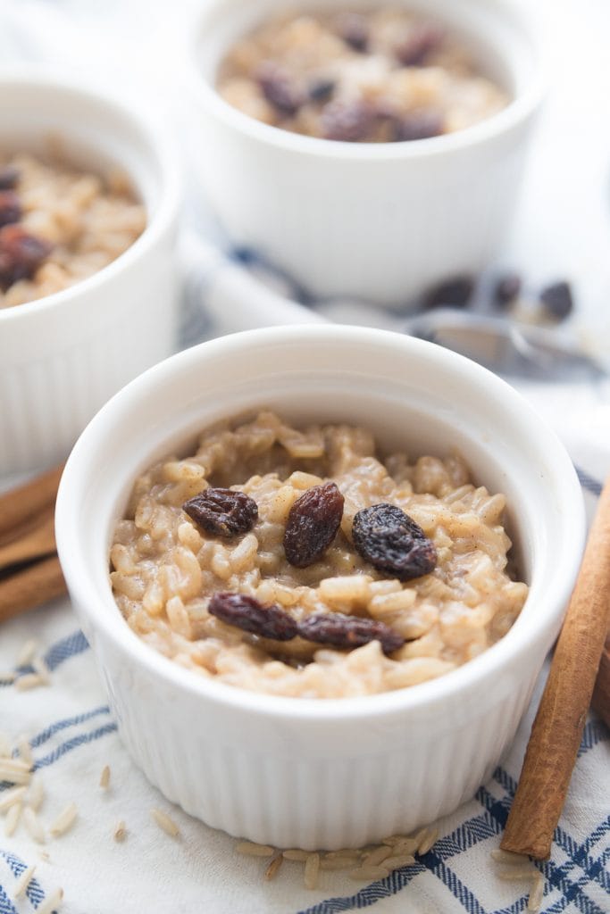 Close up of a small white ramekin with instant pot brown rice pudding topped with raisins. 