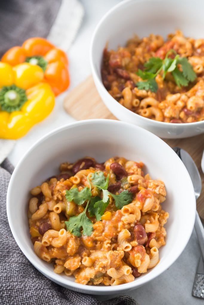 Chili mac garnished with cilantro in a white bowl