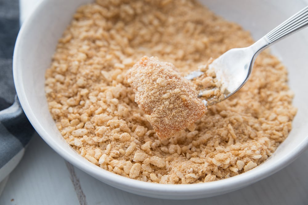 A bowl of seasoned brown rice cereal being used a breading for buffalo chicken nuggets