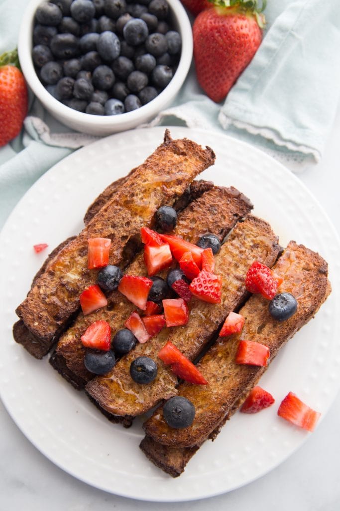 Air Fryer French Toast sticks topped with diced berries on a white plate