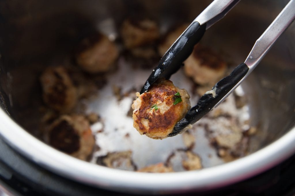 A close up shot of a browned chicken meatball over an instant pot