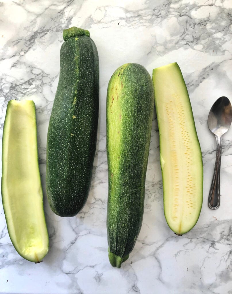 Zucchini being prepped for zucchini boats on a marble background 