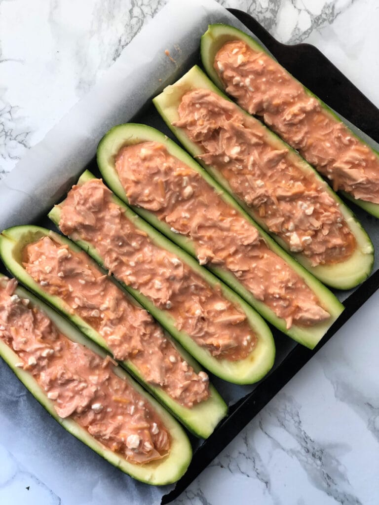 A baking sheet filled with Buffalo Chicken Zucchini Boats ready to go in the oven 