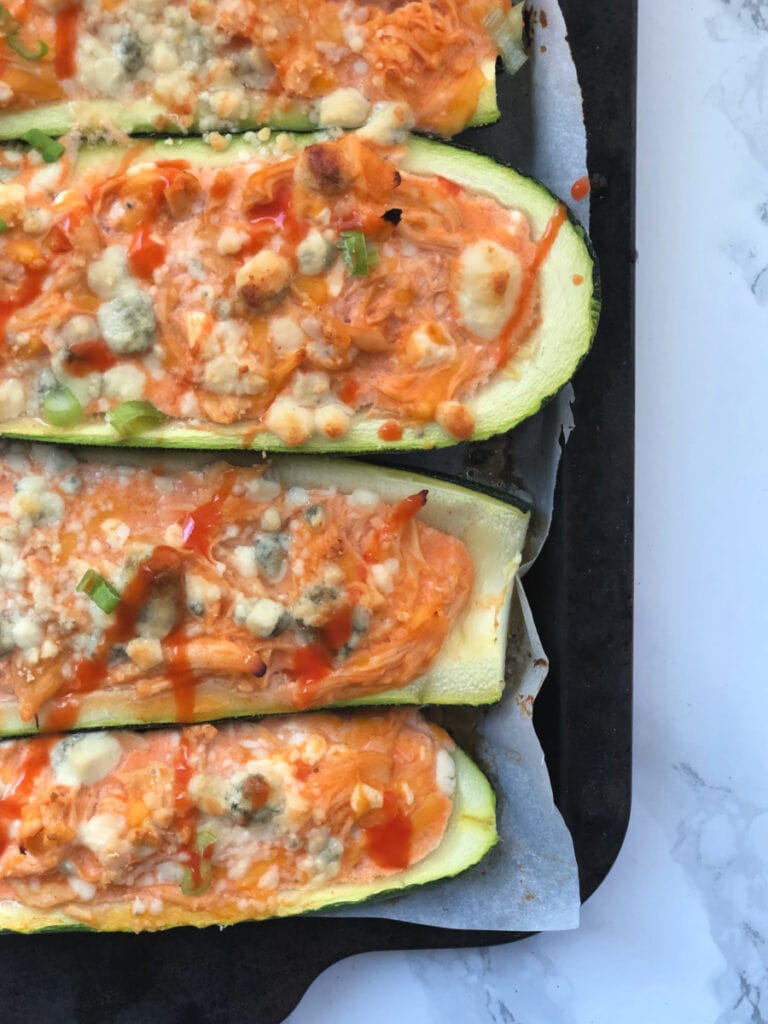 A close up of Buffalo Chicken Stuffed Zucchini Boats on a baking sheet 