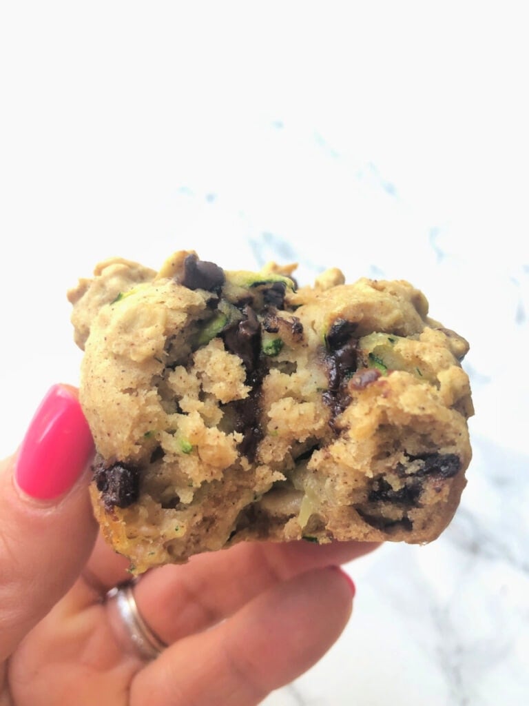 Close up of a woman's hand holding a chocolate chip zucchini muffin during brunch