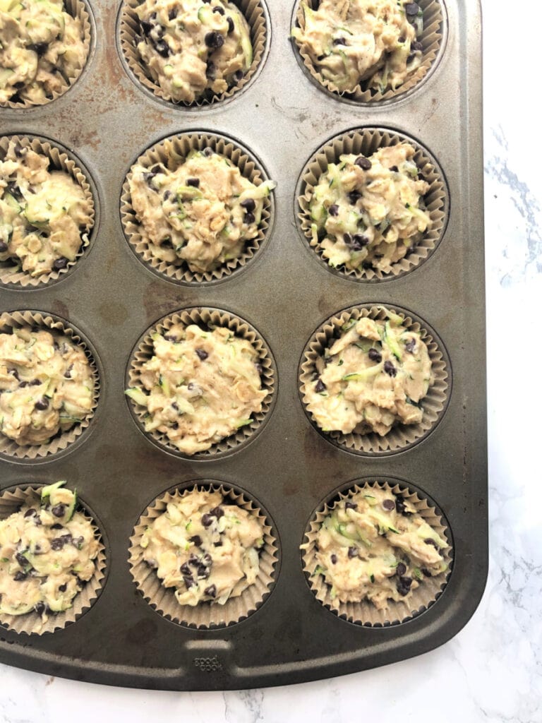 Muffin tin filled with chocolate chip zucchini muffin batter, ready for the oven