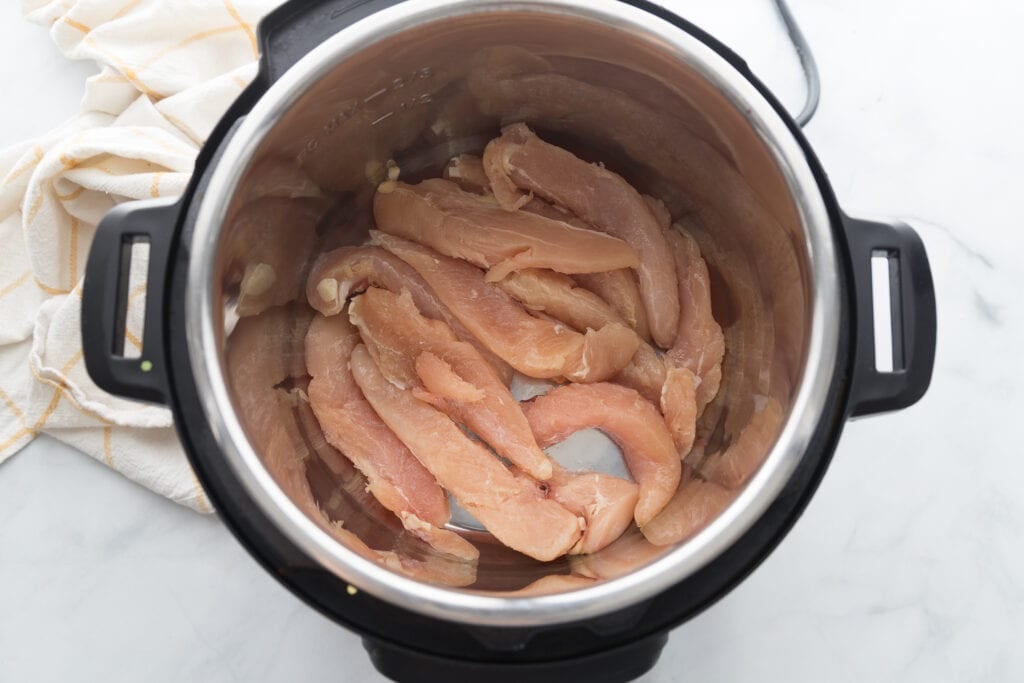 Raw chicken tenders in an instant pot, ready to be cooked