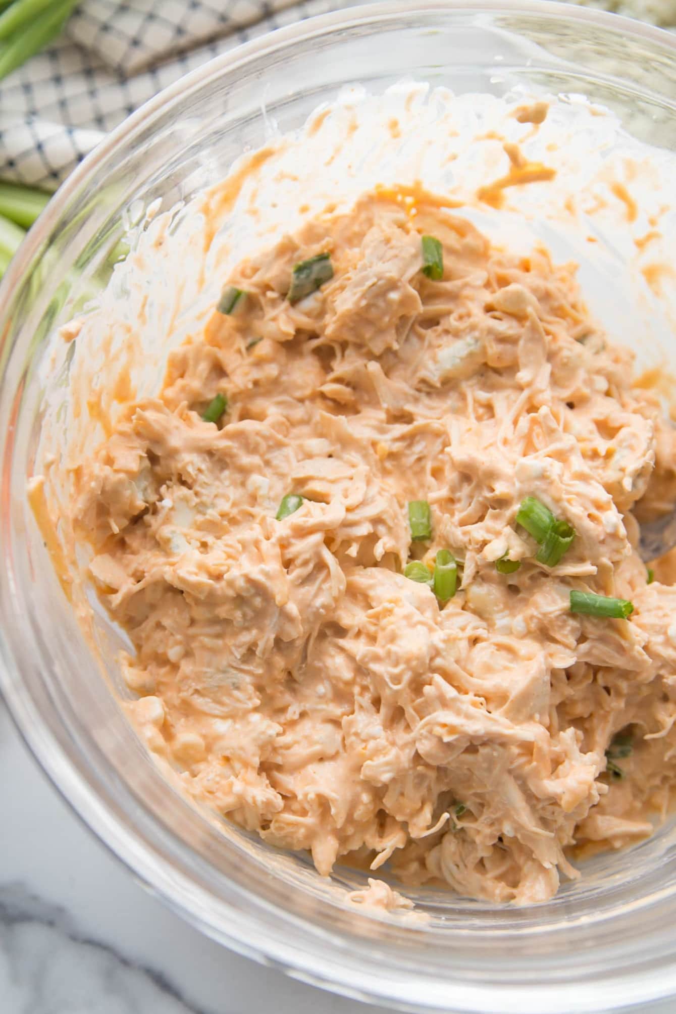 Overhead view of buffalo dip mixed with shredded chicken and topped with sliced green ontions