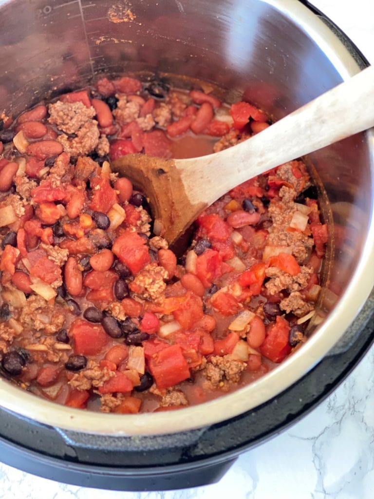 Instant Pot full of cooked 5 ingredient chili with a wooden spoon on the side