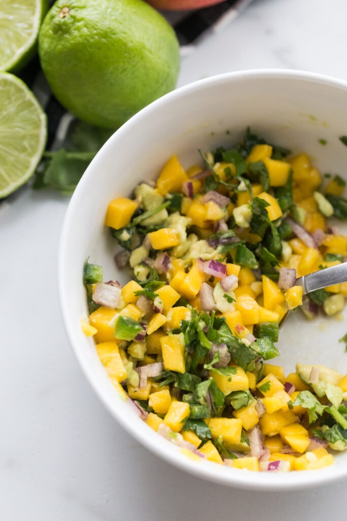 Overhead photo of a large white bowl of Mango Salsa, the perfect topping for Fish Tacos. 