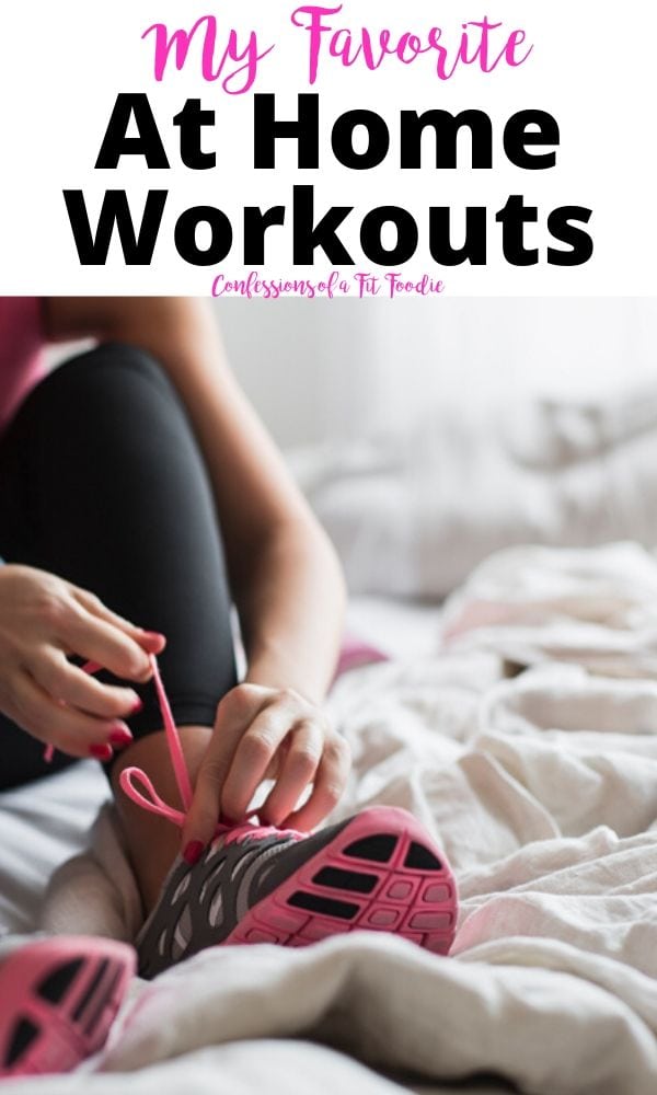 Part of a woman tying her shoes in black work out leggings. She is on a white blanket, with light coming from the background. It appears she is getting dressed for an at home workout.