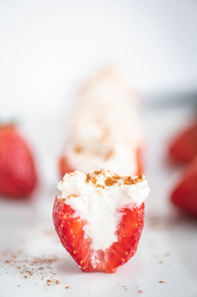 Side photo of a cross section of a cheesecake stuffed strawberry topped with cinnamon.