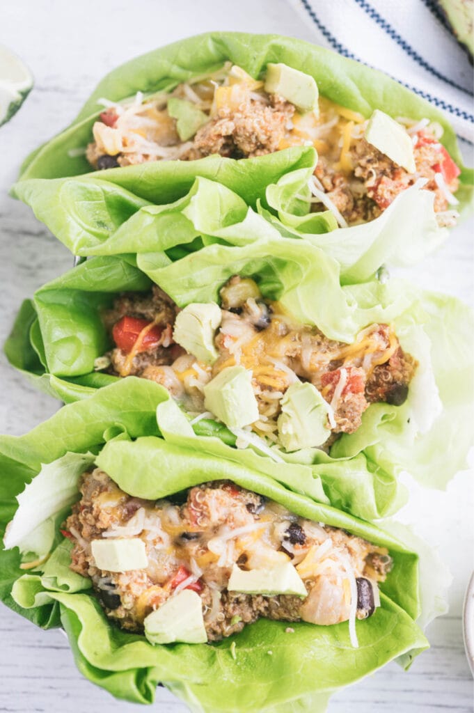 Three lettuce wraps filled with Crock pot taco casserole topped with avocado.
